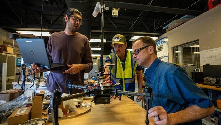 Dr. Avinash Muthu Krishnan, graduate researcher Jeremy Copenhaver and Dr. Marc Compere work on a weather-sensing drone that uses GPS to measure wind speed