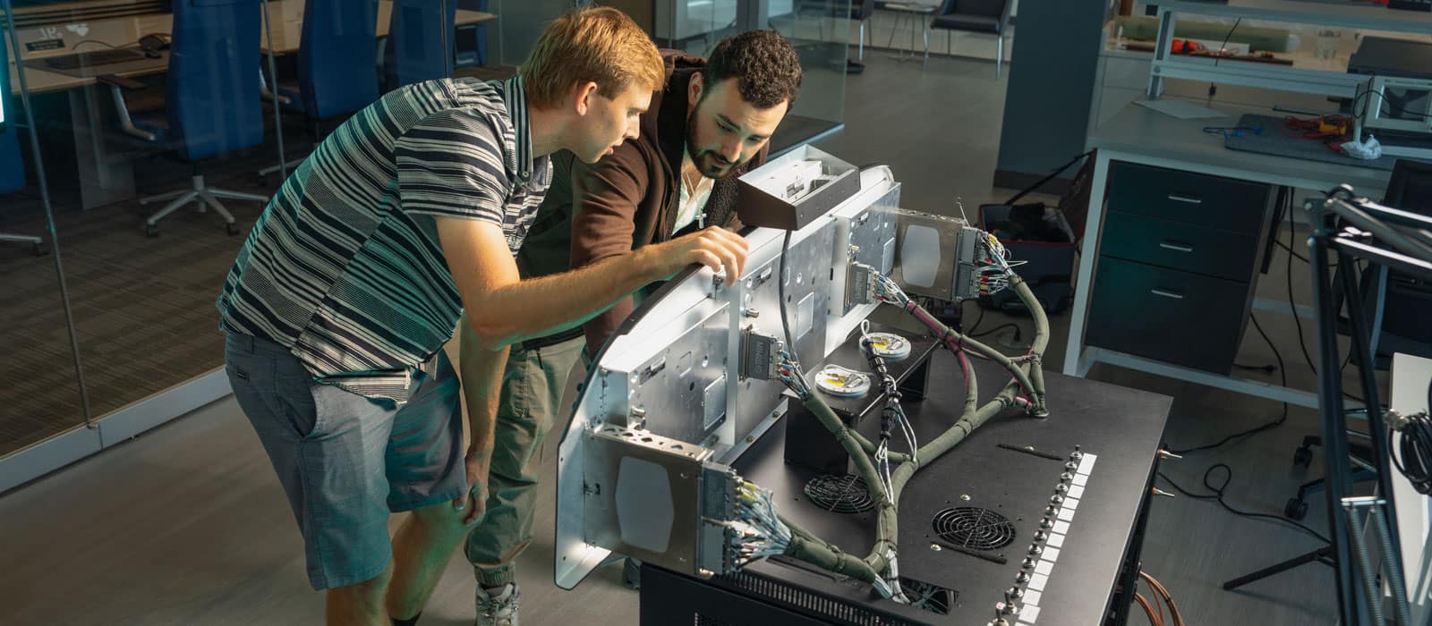 Two students work on a machine in the NEAR Lab