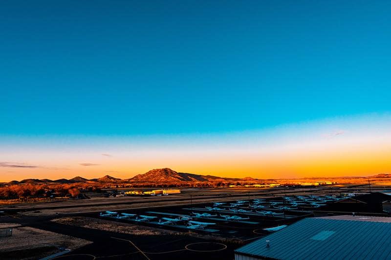 An airport apron at dawn or dusk, with Prescott's Granite Mountain in the background.