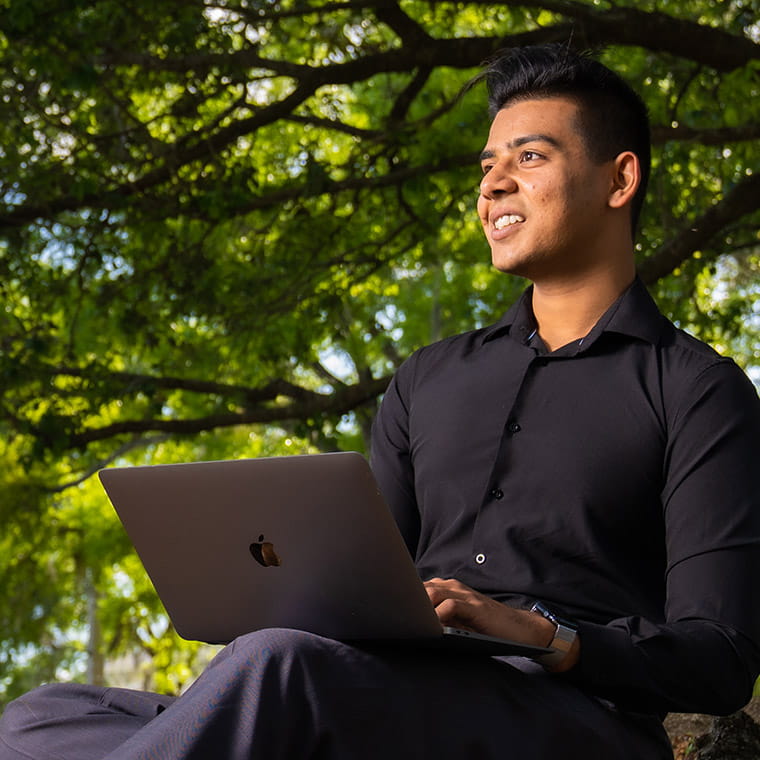 Student working on laptop computer in the sunny outdoors