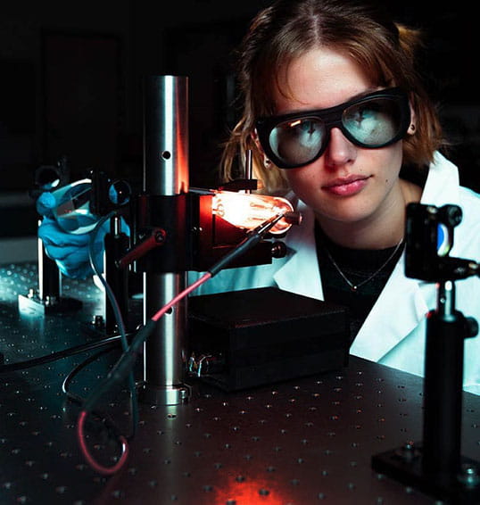 Young woman conducts tests with optical equipment in lab.