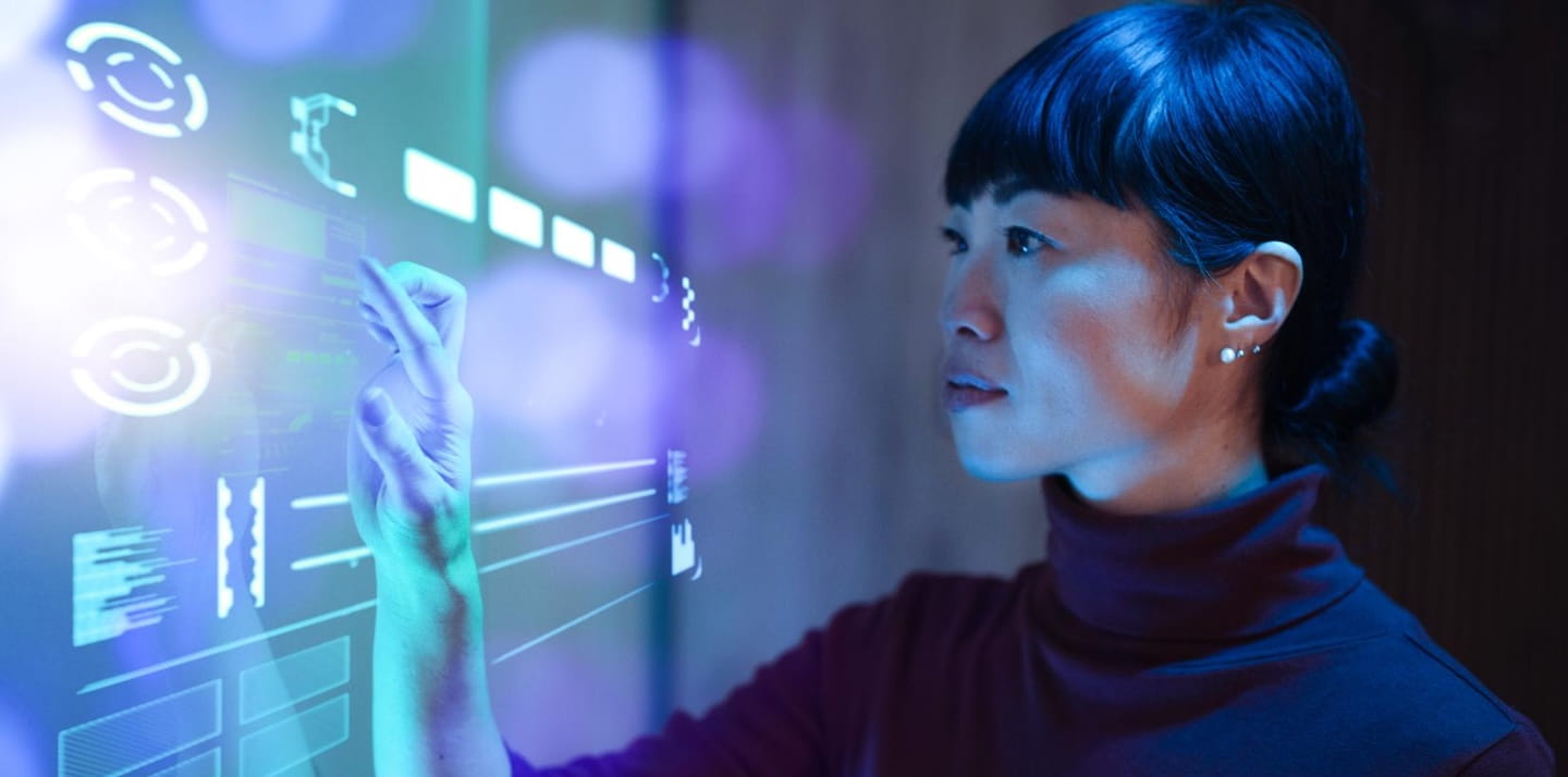 Researcher interacts with a transparent digital interface displaying data visualizations and biometric icons in a high-tech lab setting.