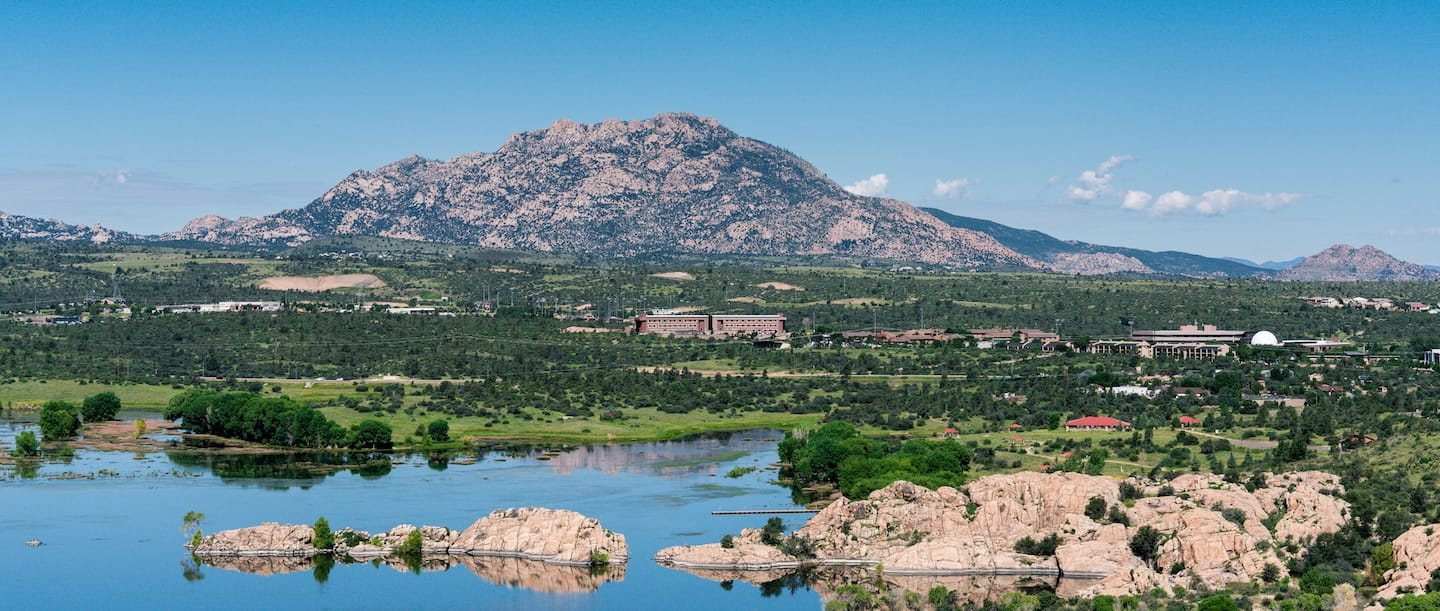 Wide view of Embry-Riddle’s Prescott campus near a lake with Granite Mountain rising in the background.
