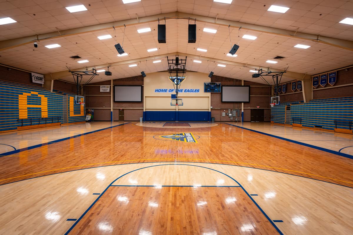 A front-facing view inside a gymnasium with the lights on.