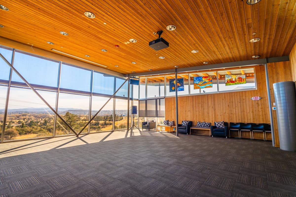 A side-angle view of a spacious interior room featuring a tall wooden ceiling and large windows that allow in plenty of natural light.