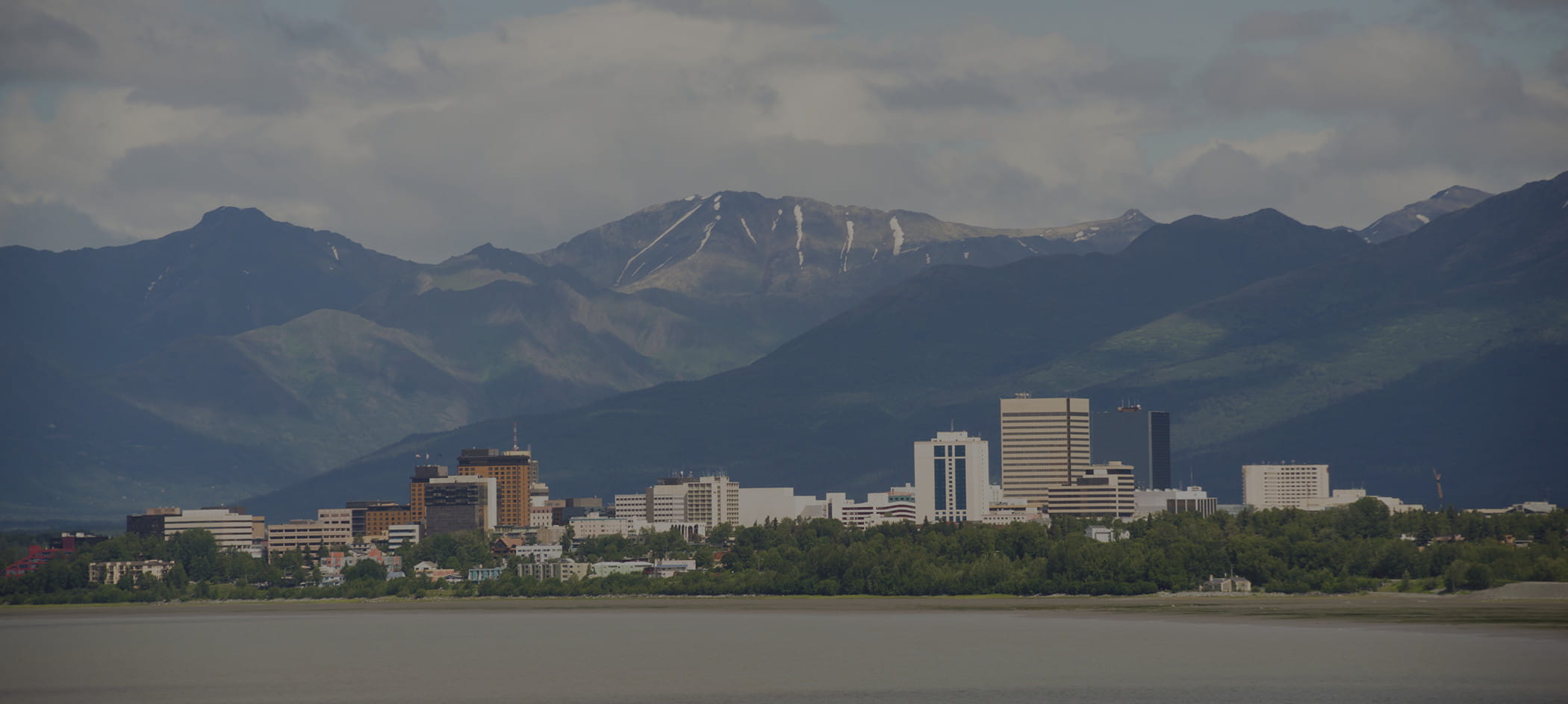 City skyline in front of Alaskan mountain range.