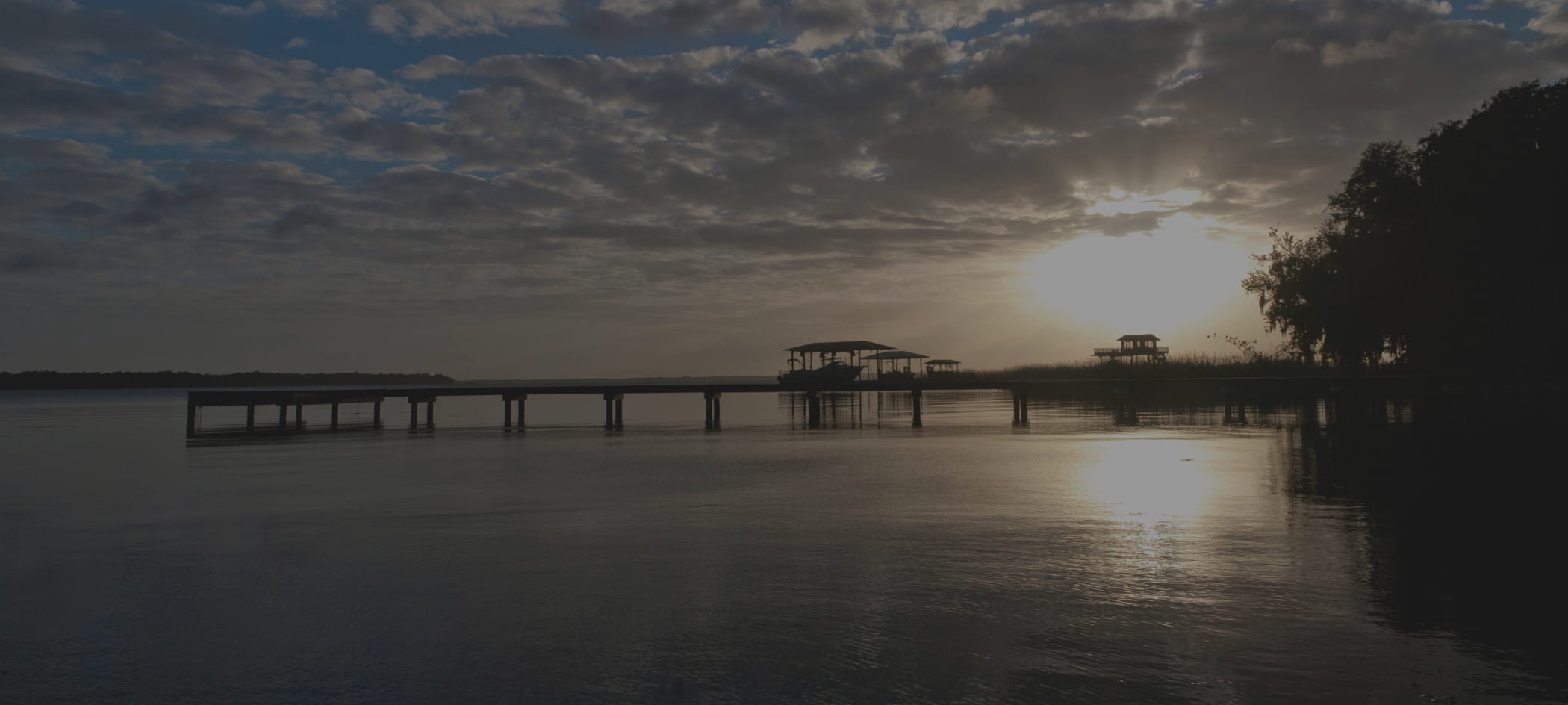 Pier over water with sunset in background.