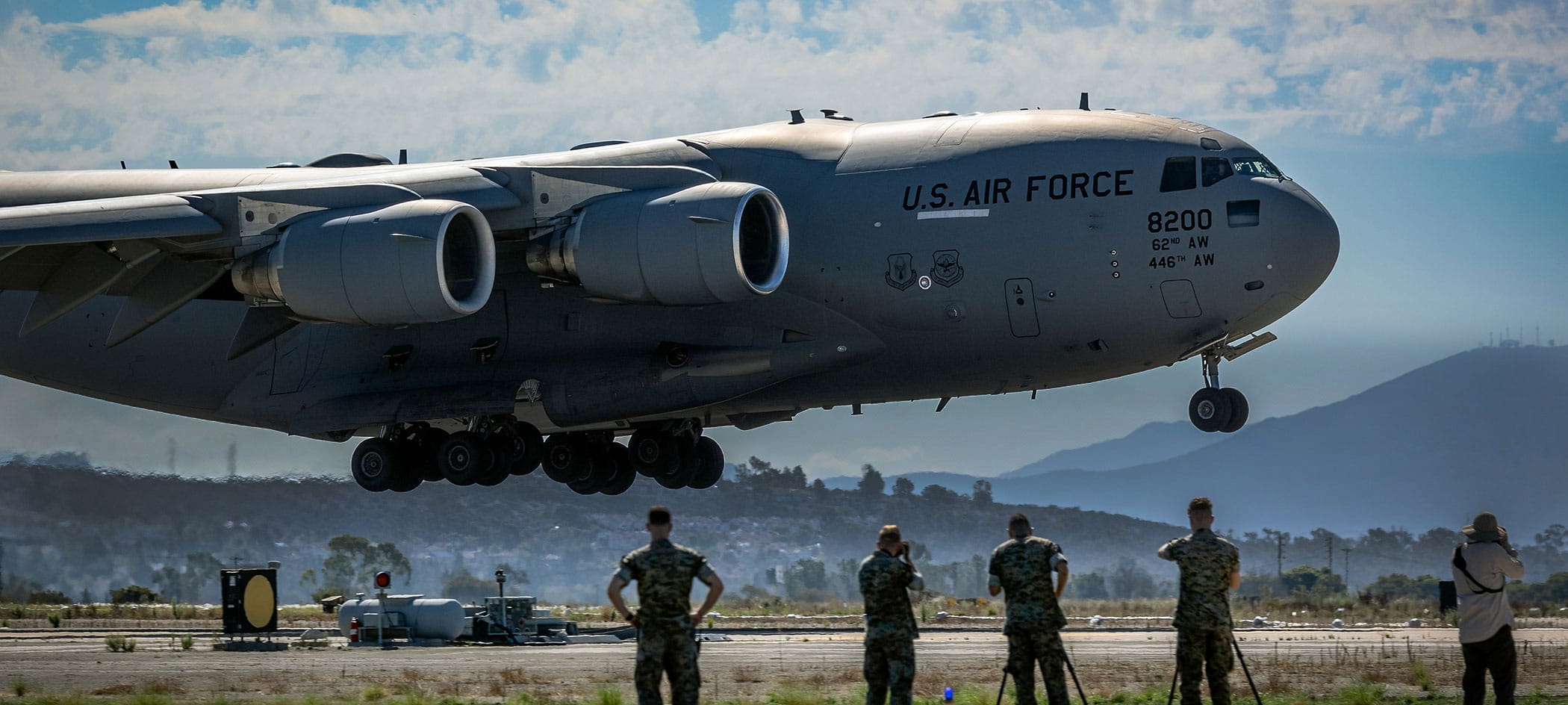 Cargo plane landing with five military soldiers watching.