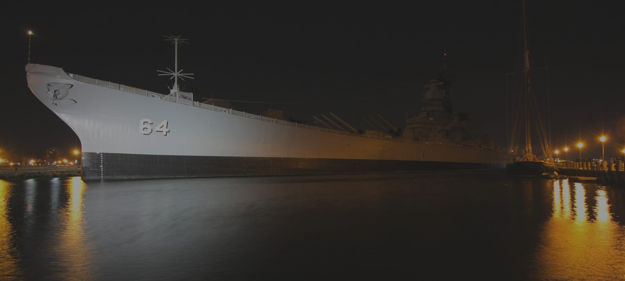 Naval ship floating in harbor at night.