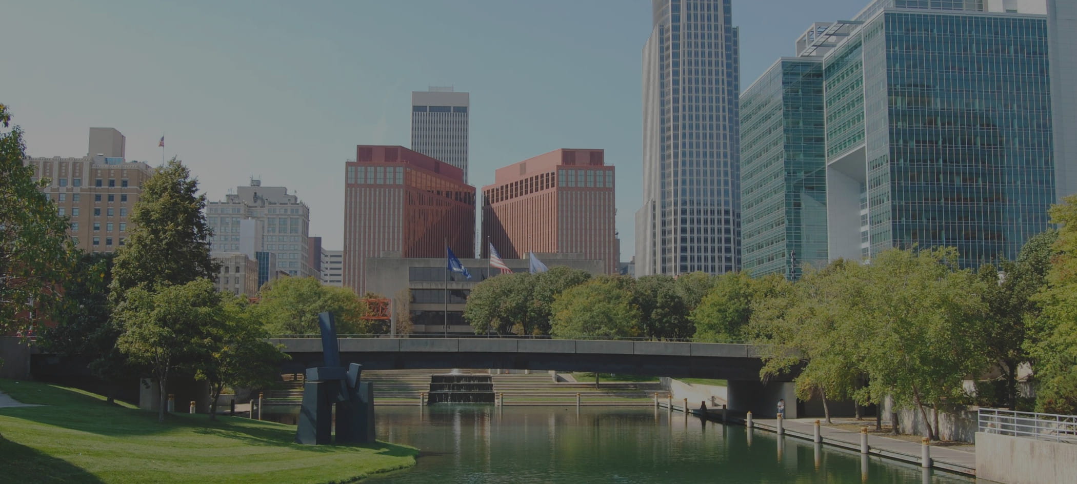City skyline with bridge and trees in forefront.