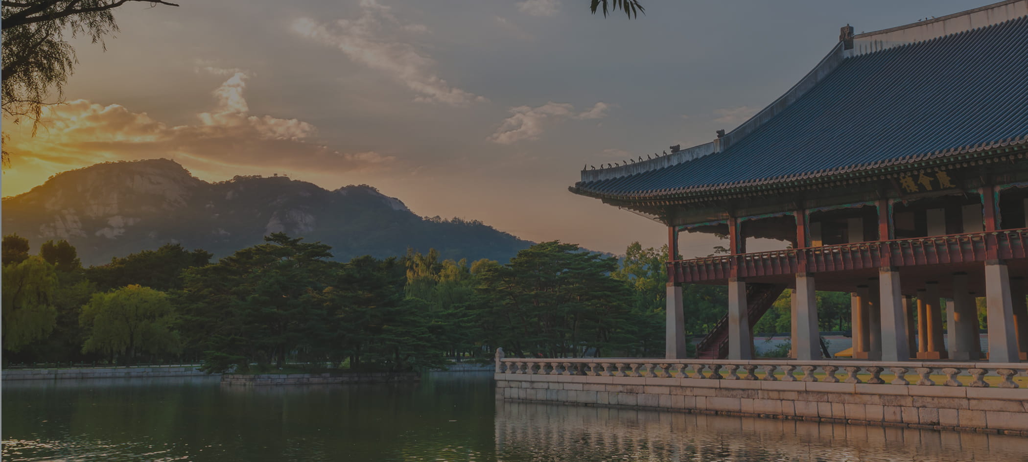 Building next to lake and mountains during sunset.