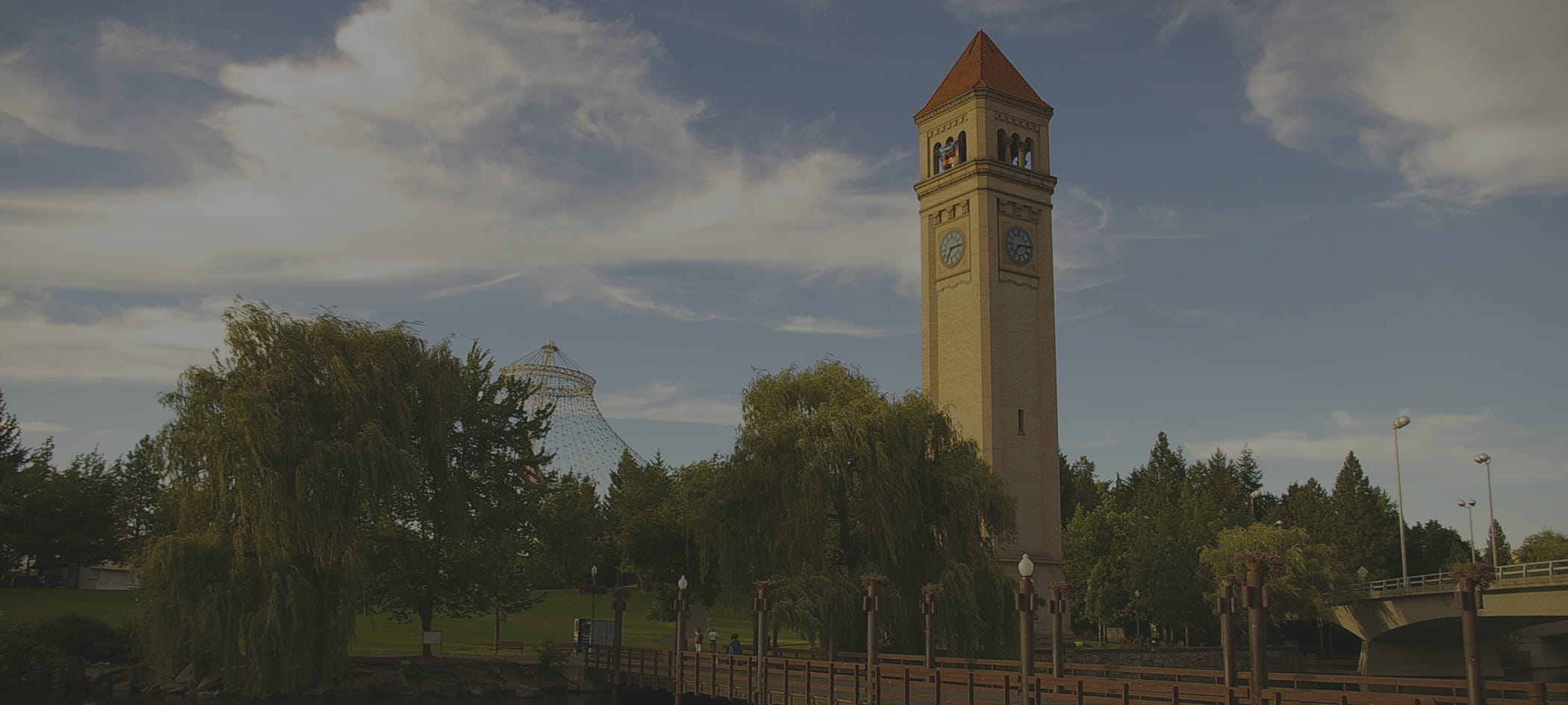 Tower stands out from trees over a blue sky.