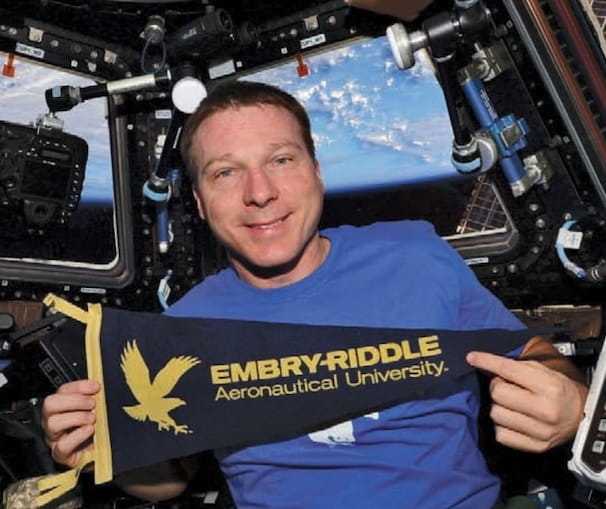 Terry Virts holds the Embry-Riddle pendant flag while in space