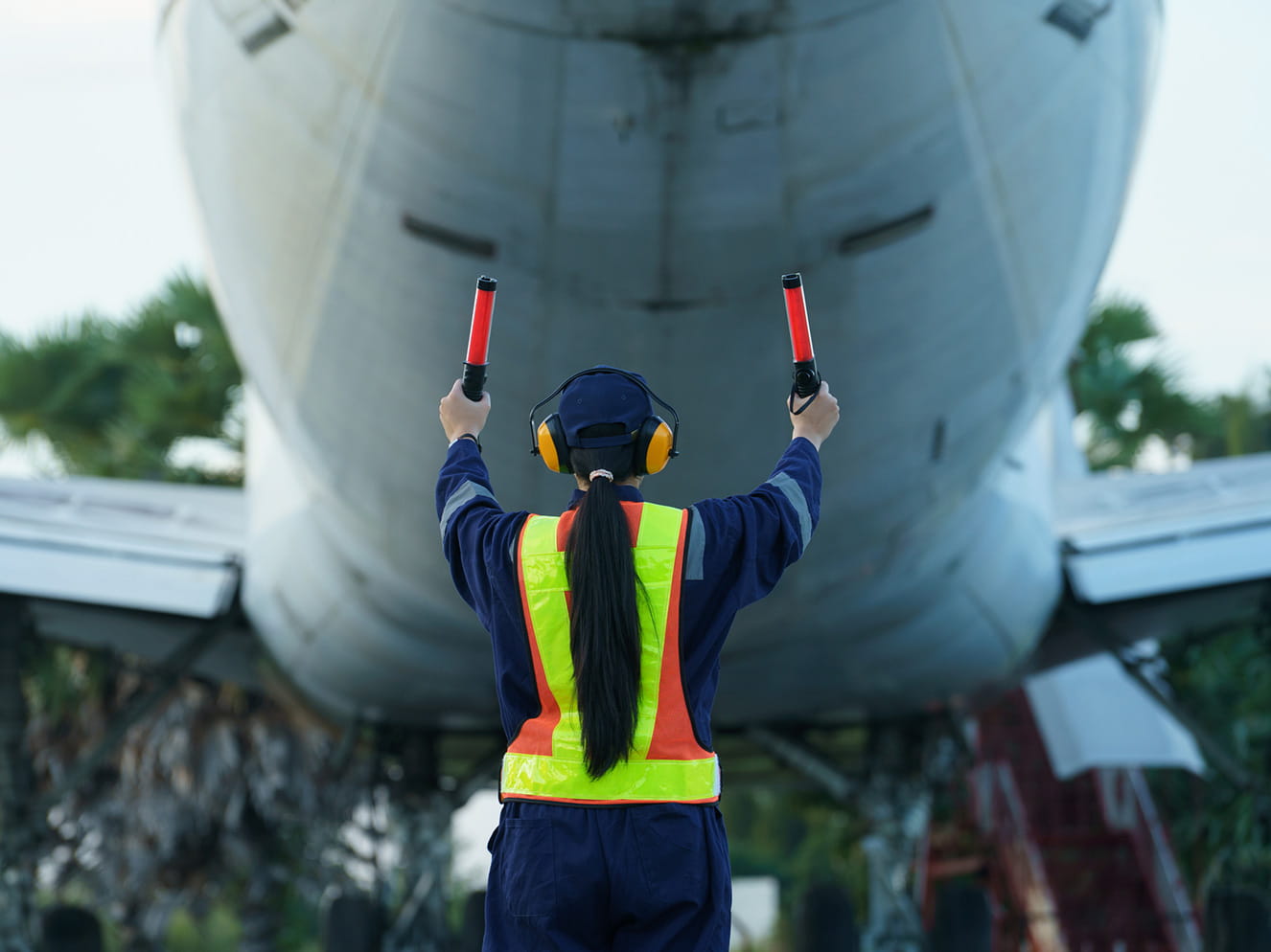 Person marshalls a plane on tarmac.