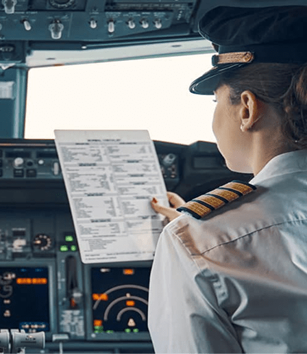 Pilot in a cockpit reviewing a printed checklist before flight.
