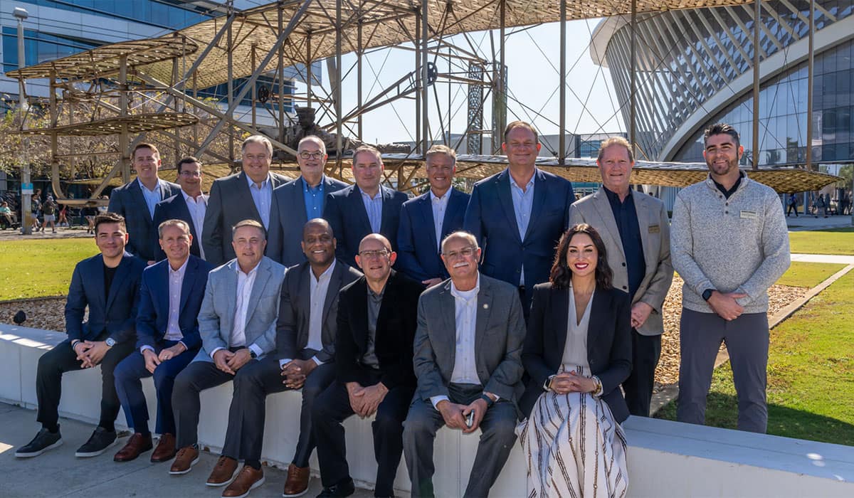 College of Aviation advisory board stands in front of a statue at the Daytona Beach campus.