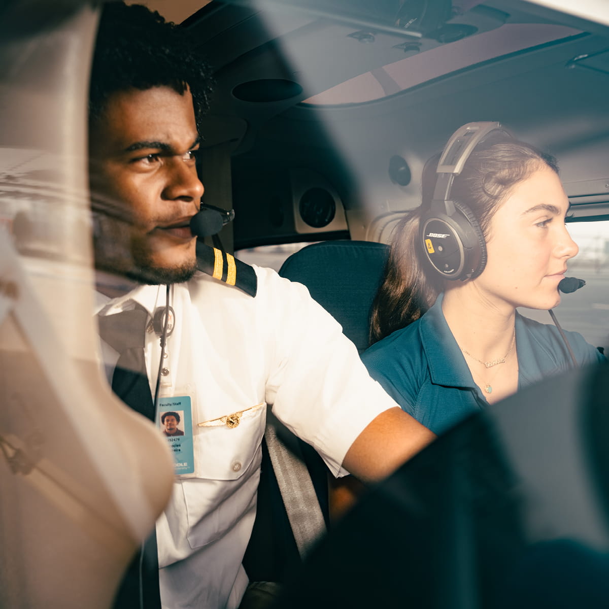Pilot and co-pilot wearing headsets seated in aircraft cockpit.