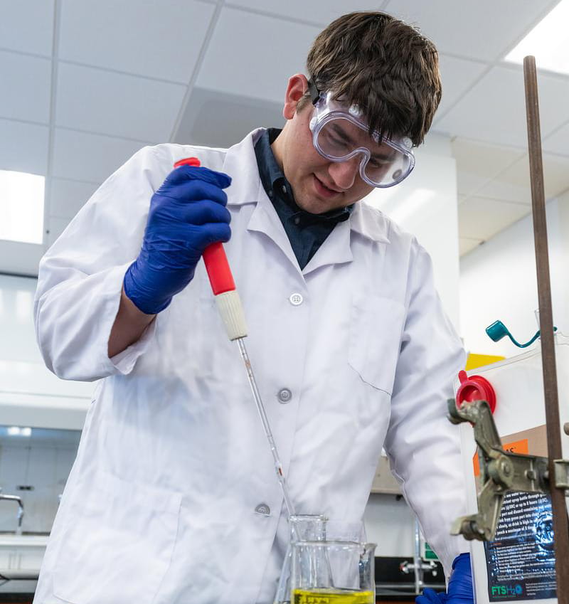 Man tests liquid with test beaker and baster.