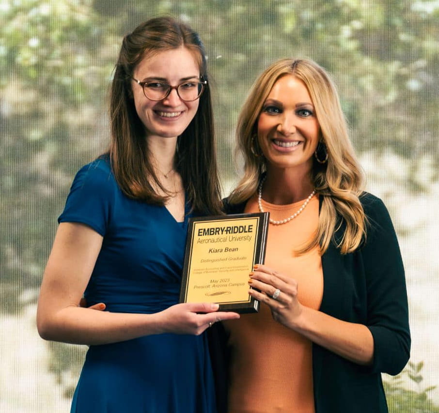 Kiara Beach stands with a professor and accepts the distinguished graduate award