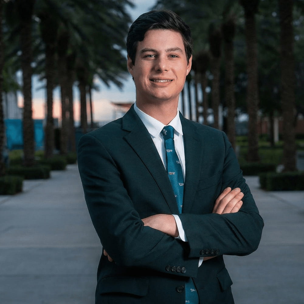 Peyton Stikeleather stands in a business suit on the Daytona Beach campus, crossing his arms