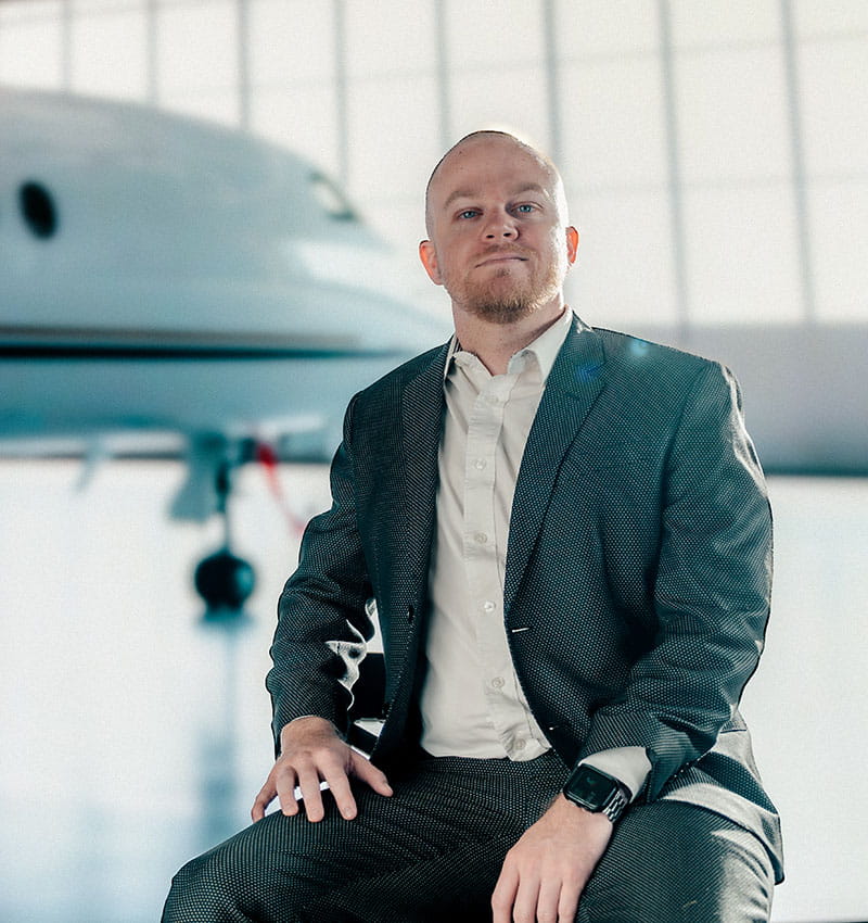 Student sits in a hangar in front of an airplane