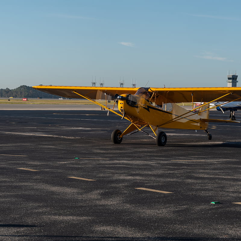 A small yellow plane sits on the tarmac