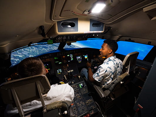 Two Embry-Riddle students sit in a flight simulator