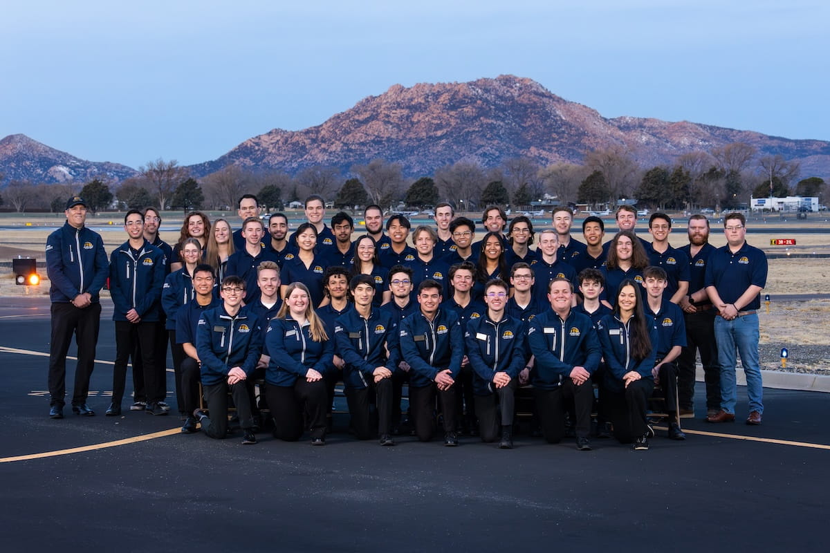 The Golden Eagles team lines up for a photo on the tarmac at the Embry-Riddle Prescott campus as a mountain looms in the background