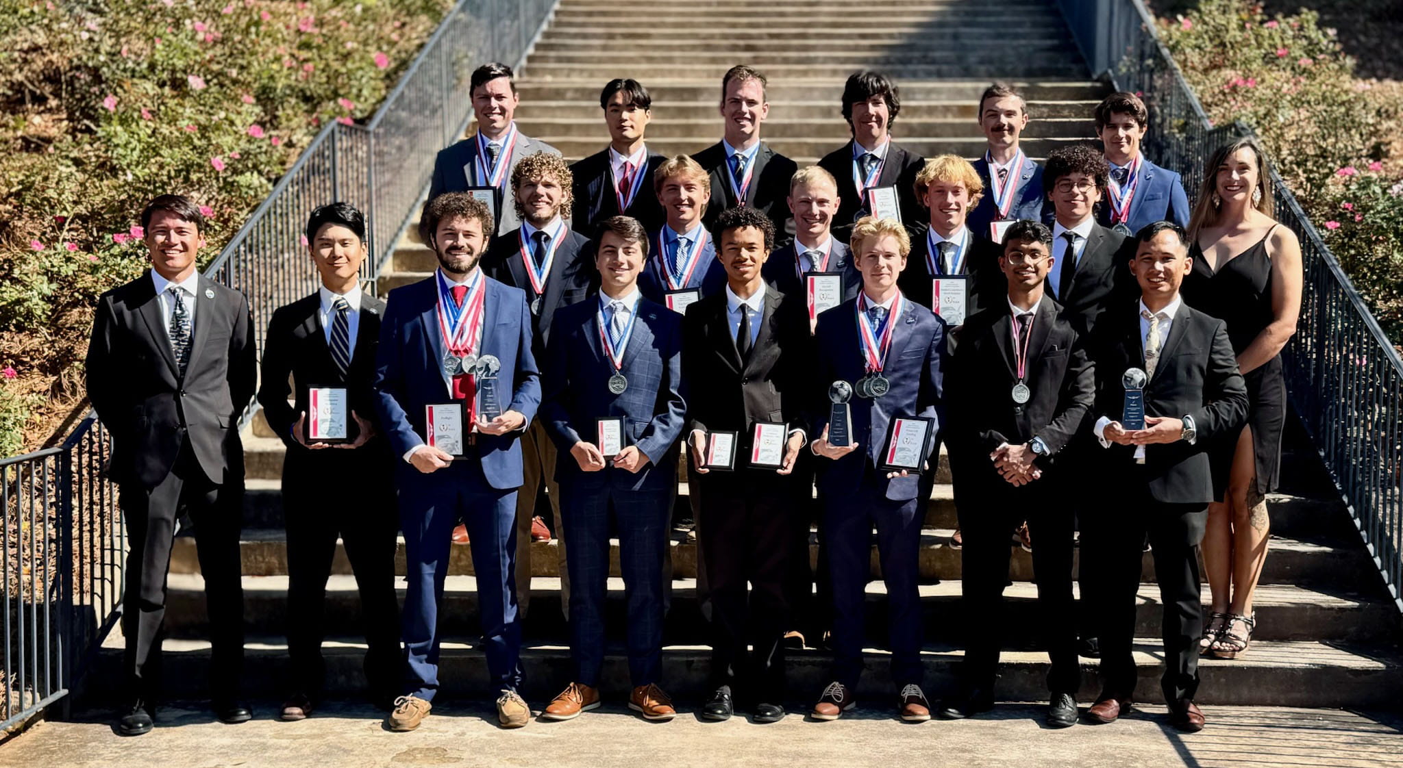 The Embry-Riddle Eagle Flight Team stands together in professional dress holding their awards