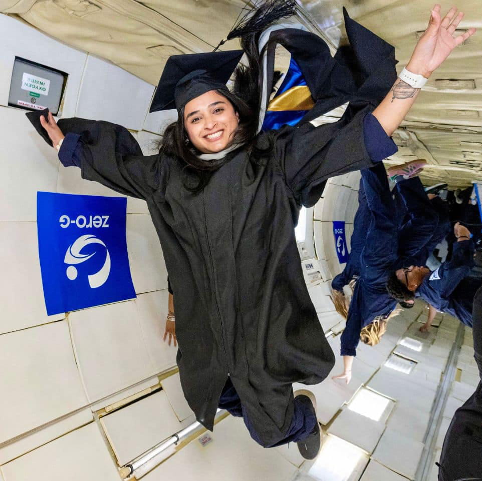 Shay Bhardwaj wears a cap and gown and floats in a zero gravity chamber