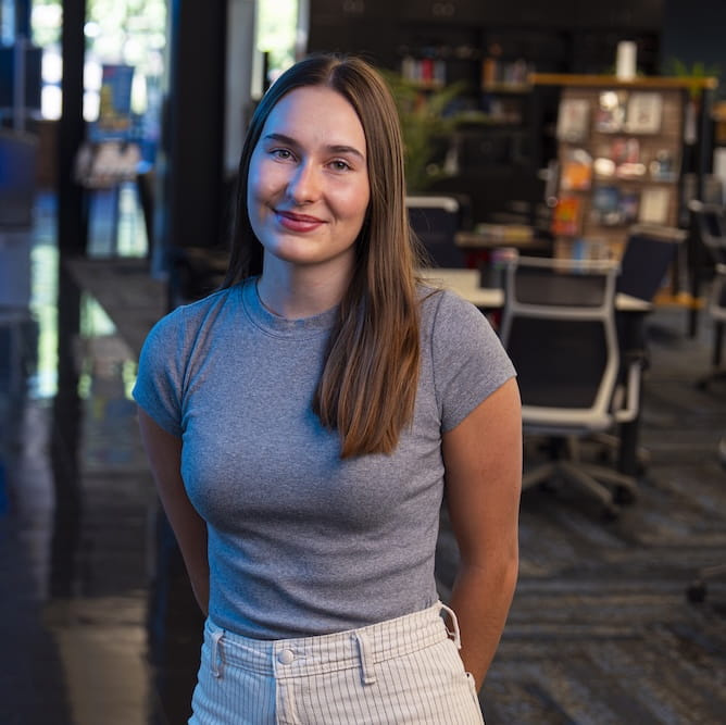 Chloe Nelson stands in the lobby of a building on campus