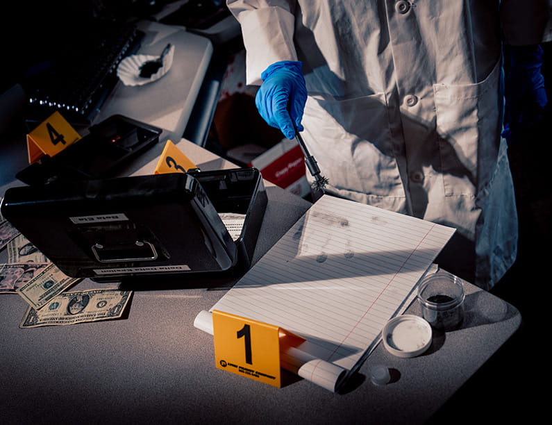 A person in a lab coat dusts items for fingerprints