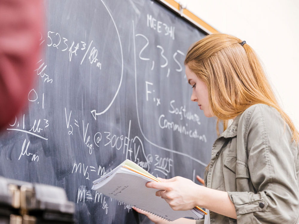 Woman at a board doing math.