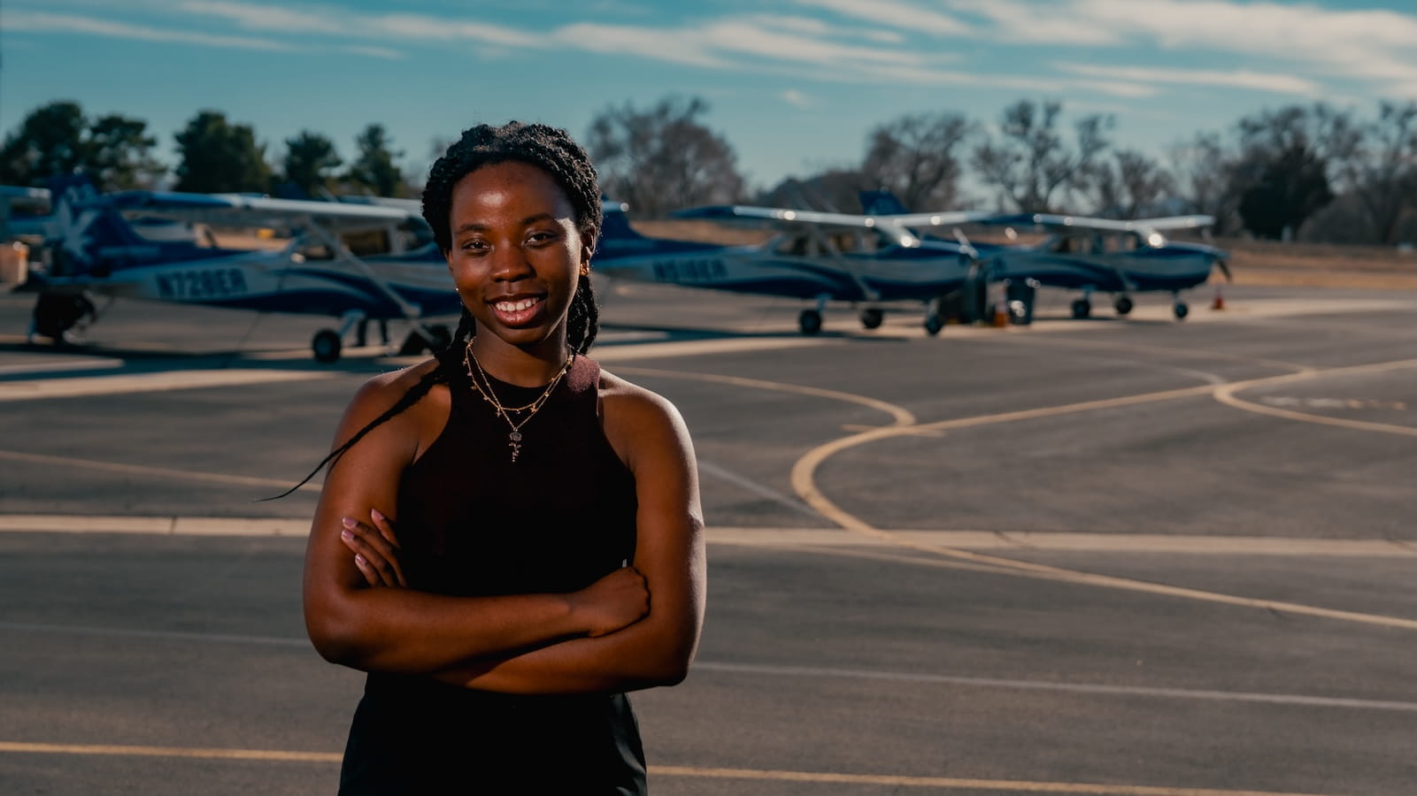 Megan Yaa Amoako stands on the tarmac with parked airplanes behind her
