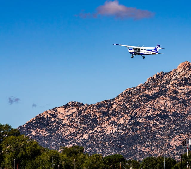 A small airplane flies over the mountains of Arizona