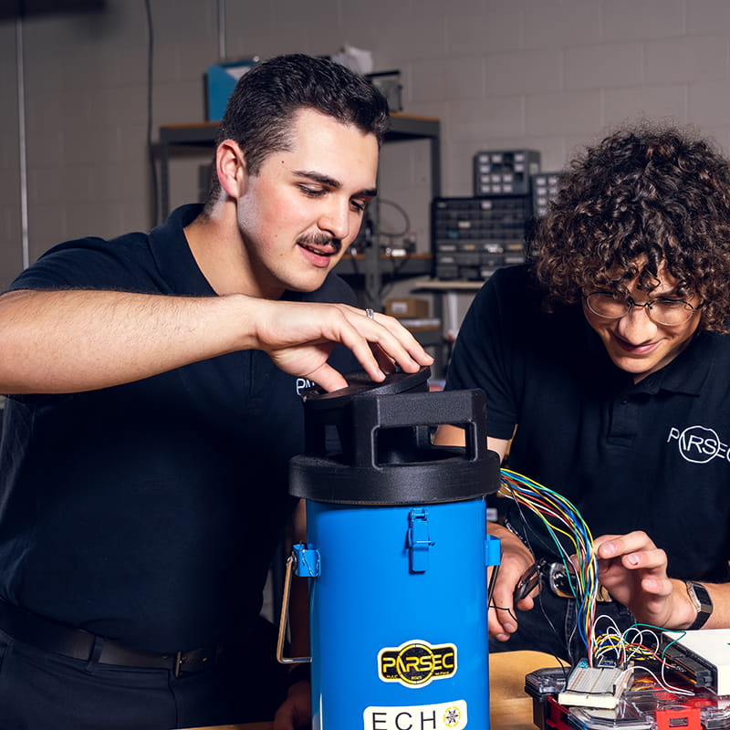 Two Embry-Riddle students work on a piece of equipment in a lab