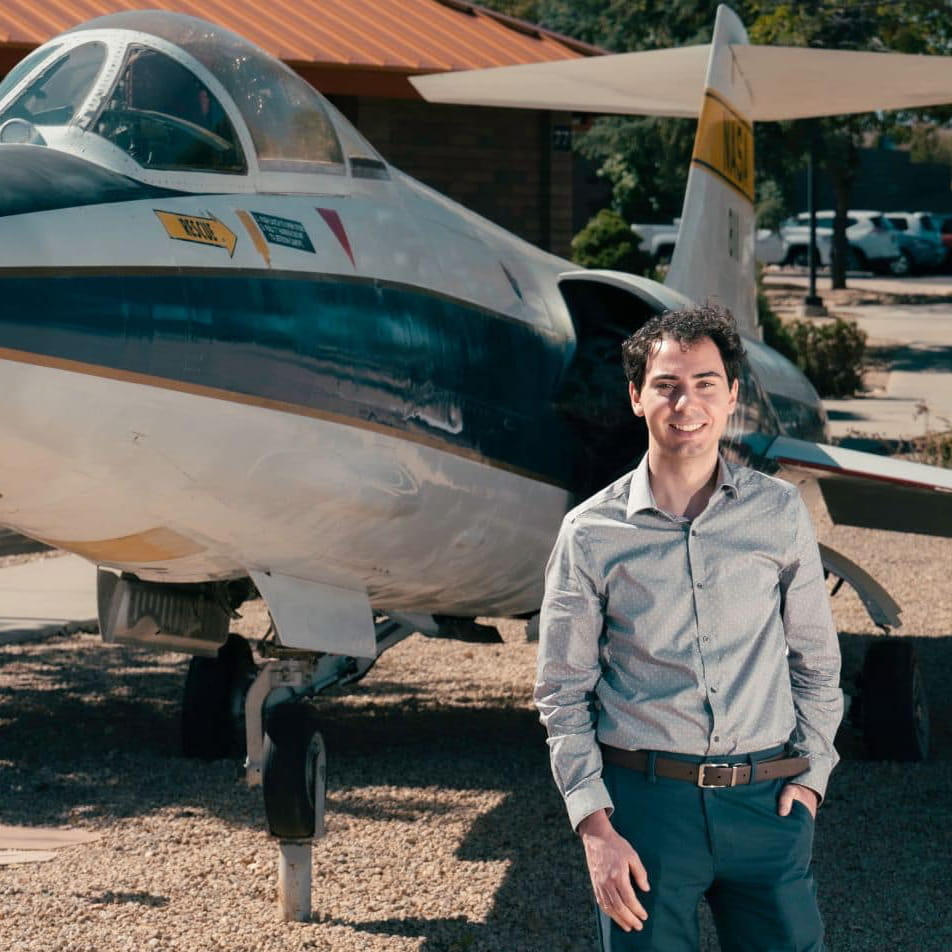 Adam Moore stands in front of a small plane