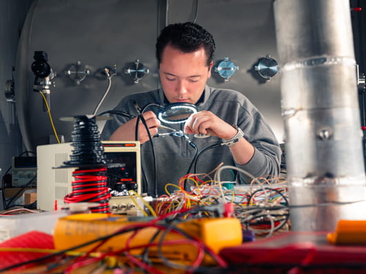 A person working on electrical equipment in a lab setting.