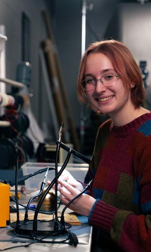 A person smiling for the camera while working on electrical equipment.
