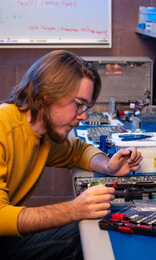 A person conducting research on electrical equipment in a lab setting.