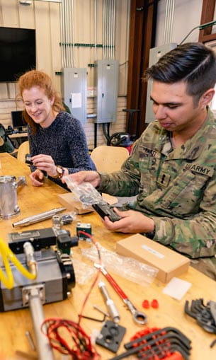 Two people sitting in a lab, working on equipment.