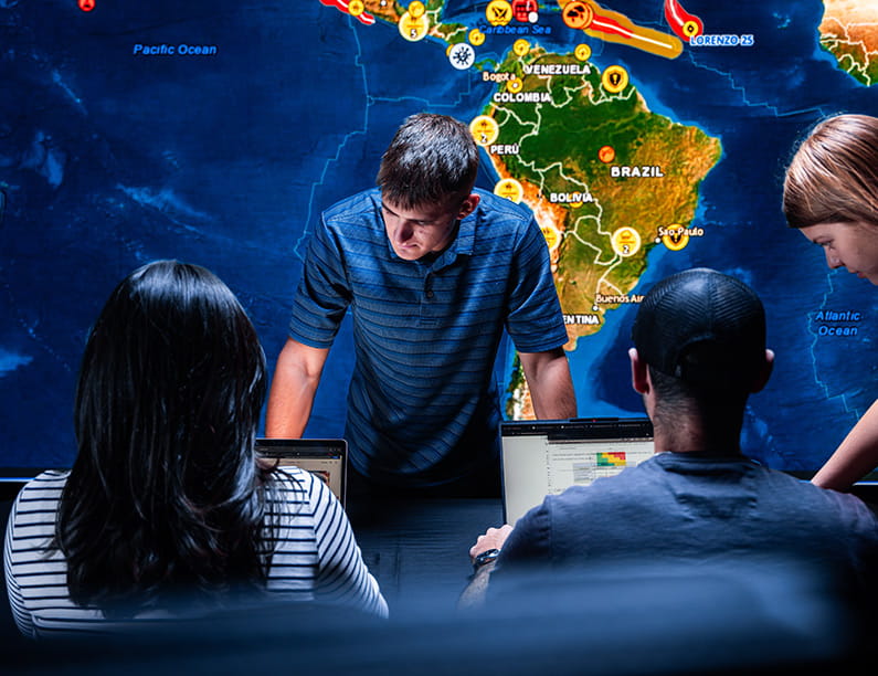 A group of people in a room with a world map in the background