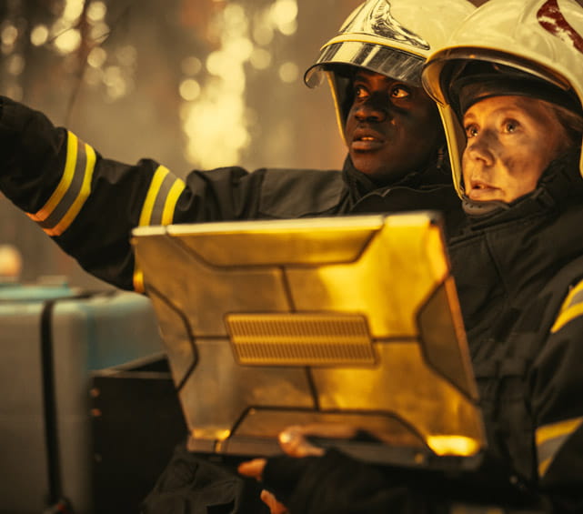 Two firefighters standing together looking at a laptop.