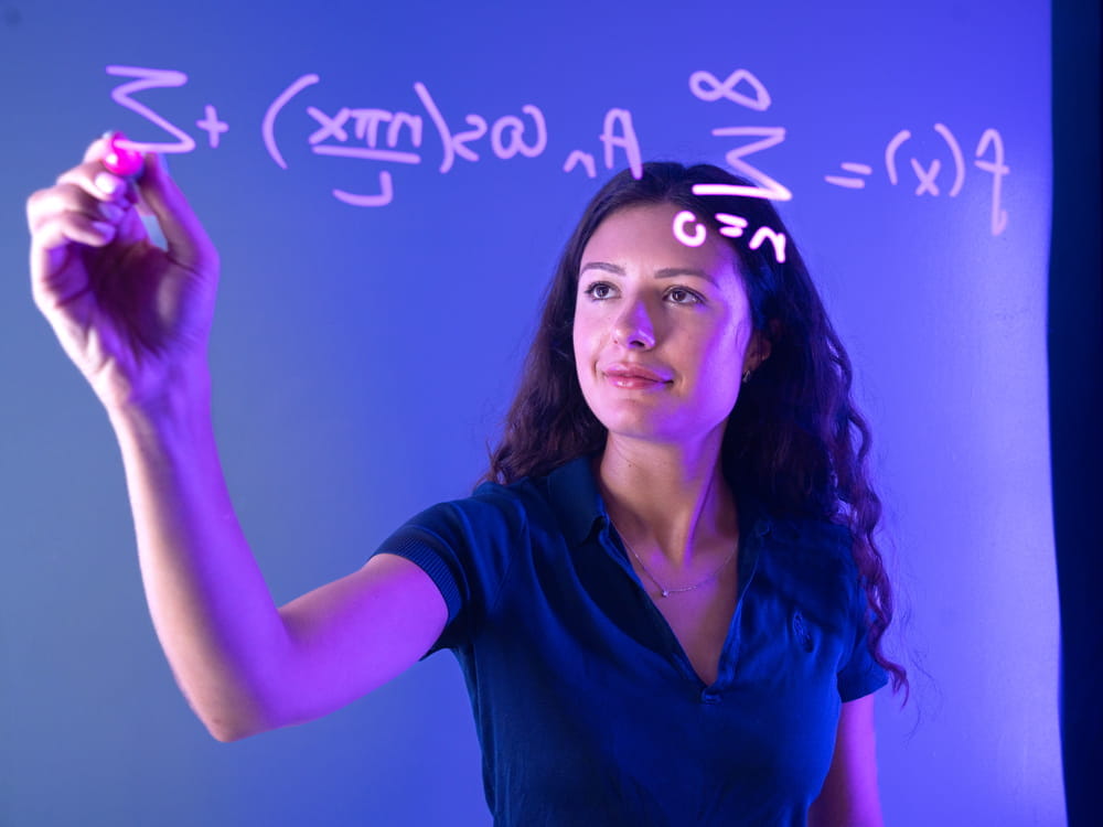 Embry-Riddle student in a business suit stands at the front of a room presenting analytics