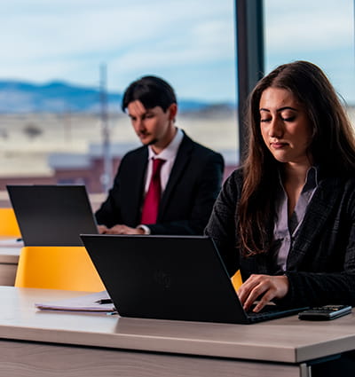 Embry-Riddle Worldwide students work on laptops overlooking the tarmac