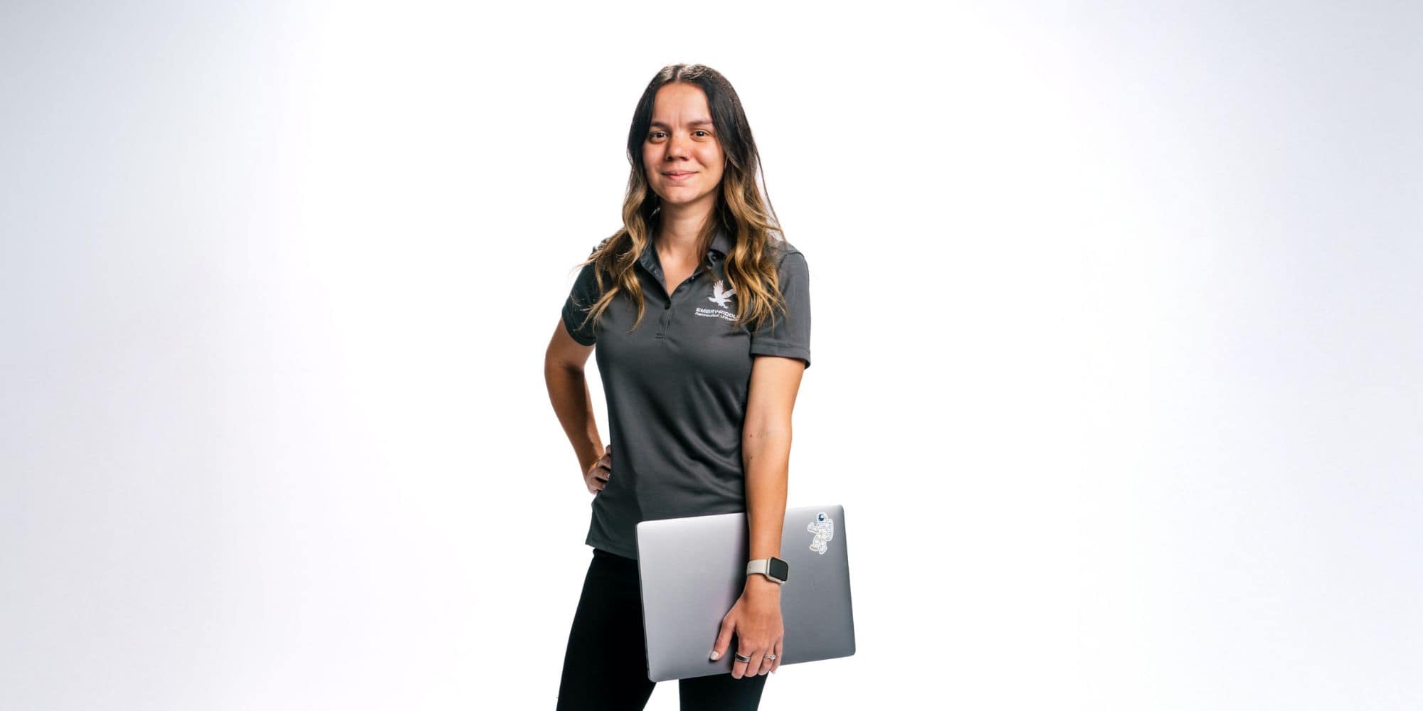 Ashley Strickland stands confidently holding her laptop by her side.