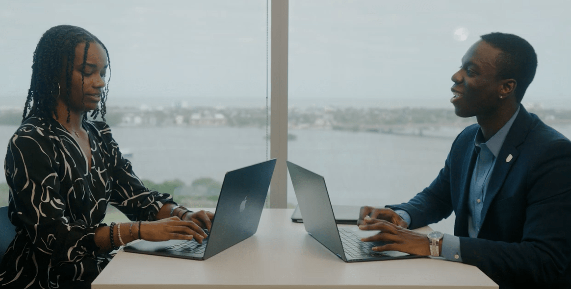 Two people sitting at a table, working on their laptops.