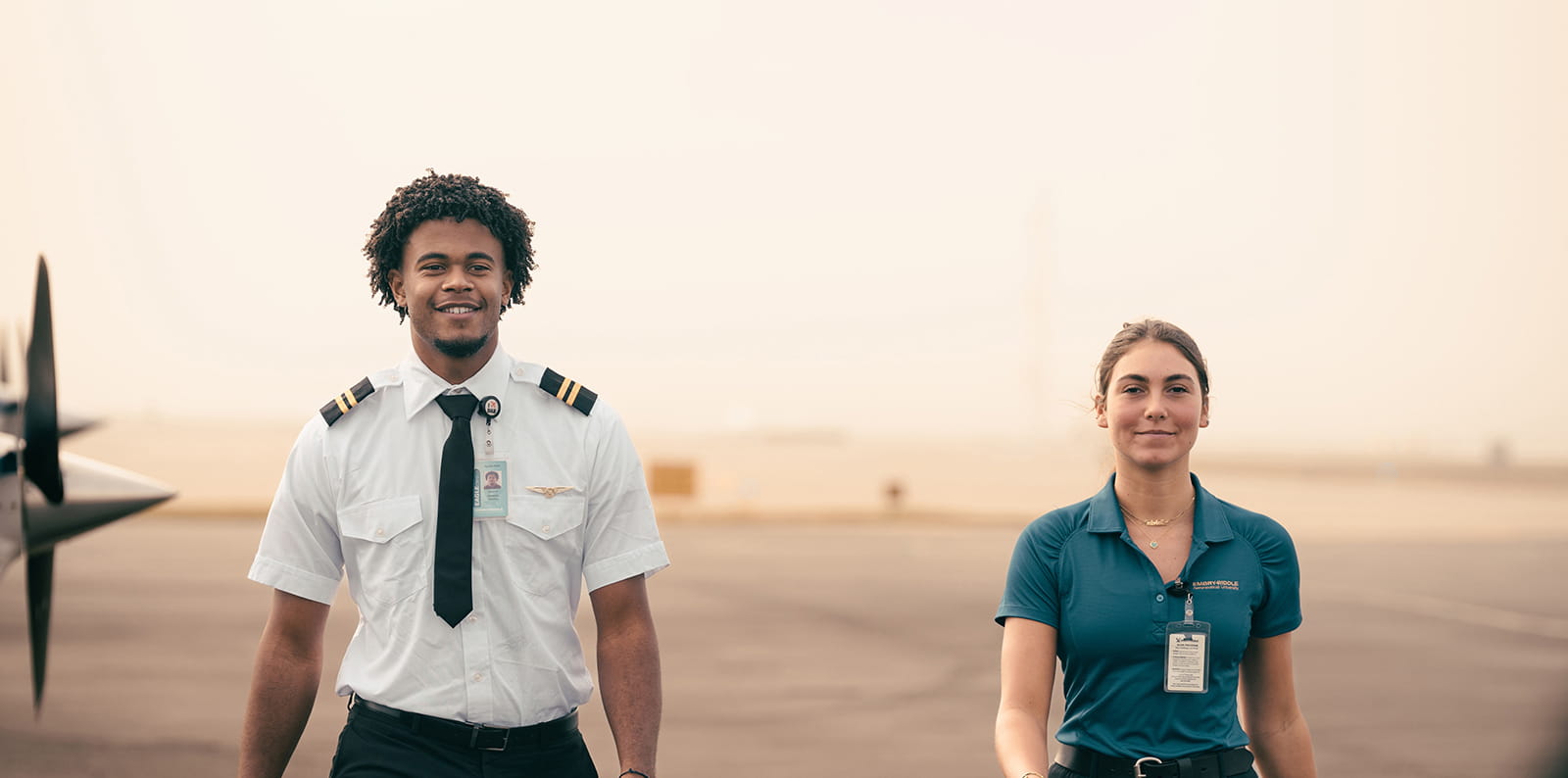 A pilot and a person in a polo walk on the tarmac toward a plane