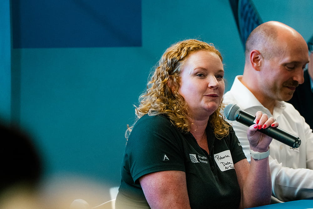 An Embry-Riddle instructor holds a microphone and presents at a conference