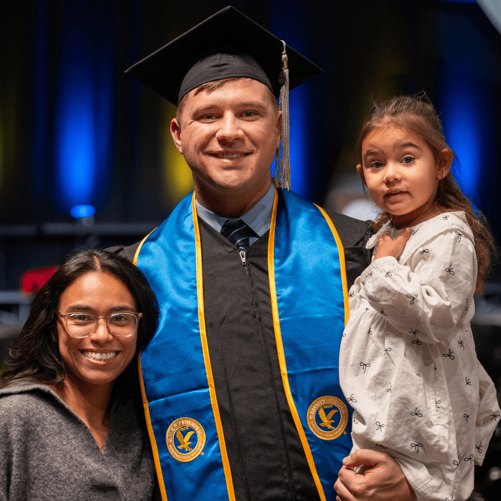 Dustin Foote stands with his family in a graduation cap and gown